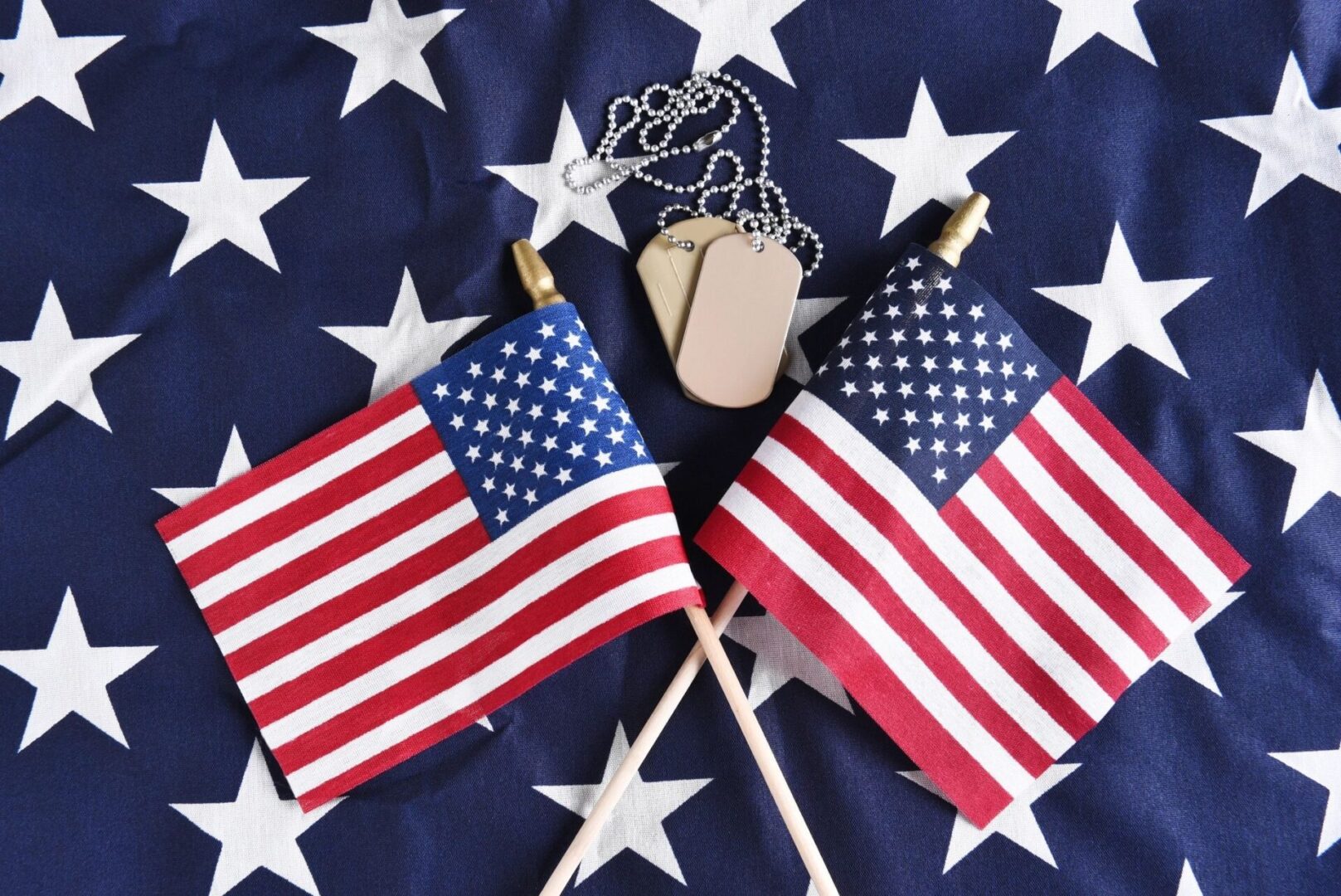 Two american flags with a dog tag on top of them.