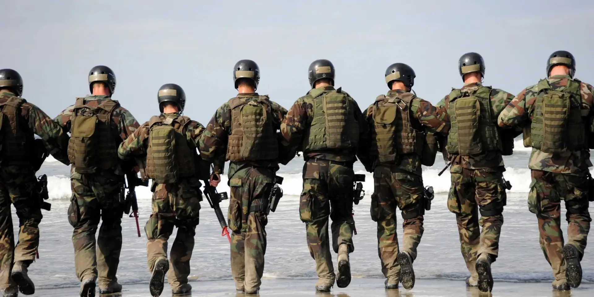 A group of soldiers walking along the beach.